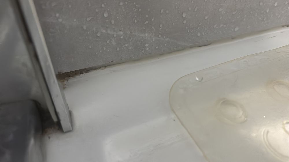 Wall tiles not carried over the shower tray upturn, with the sealant deteriorated, found during a defect investigation inspection in Epping