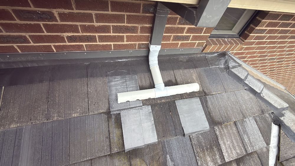 Downpipe spreader discharging onto tiles beside the valley, keeping the area wet, found during a defect investigation inspection in Mernda